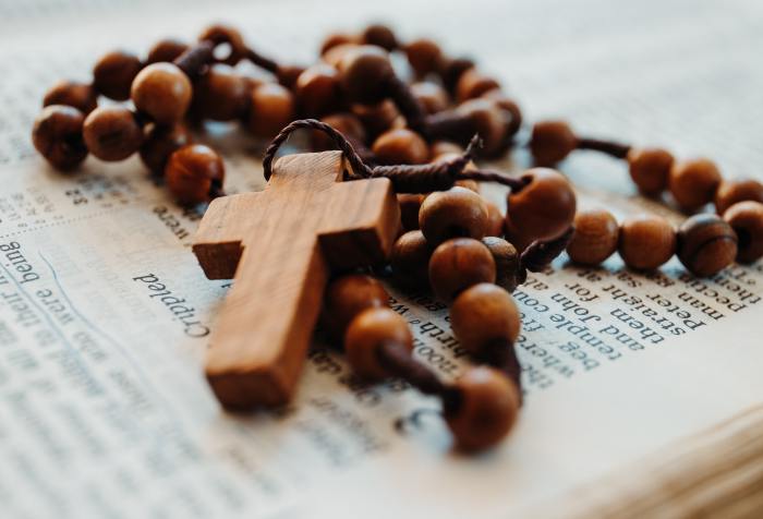 wooden prayer beads sitting on top of an open Bible with the word crippled clearly visible
