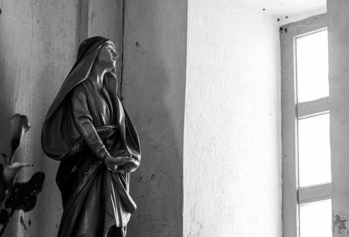 a religious statue looking out of a church window black-and-white
